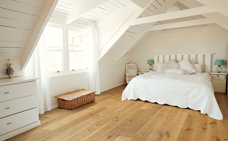 warm toned hardwood flooring in attic bedroom